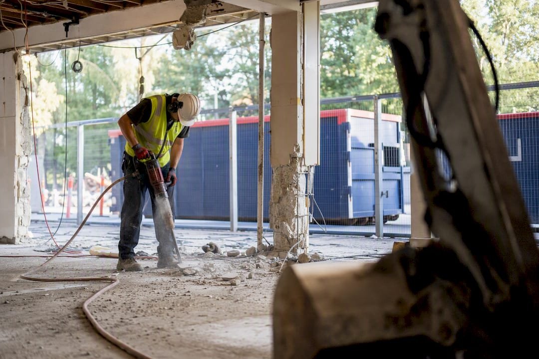 Demolition worker manually stripping concrete floor