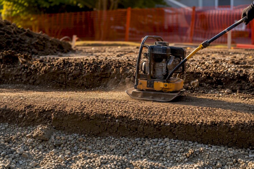 Compacting layered backfill soil with plate compactor