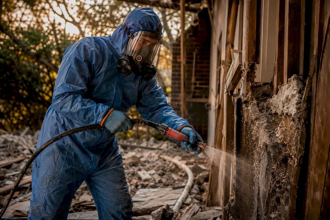 Technician applying wet spray barrier on asbestos