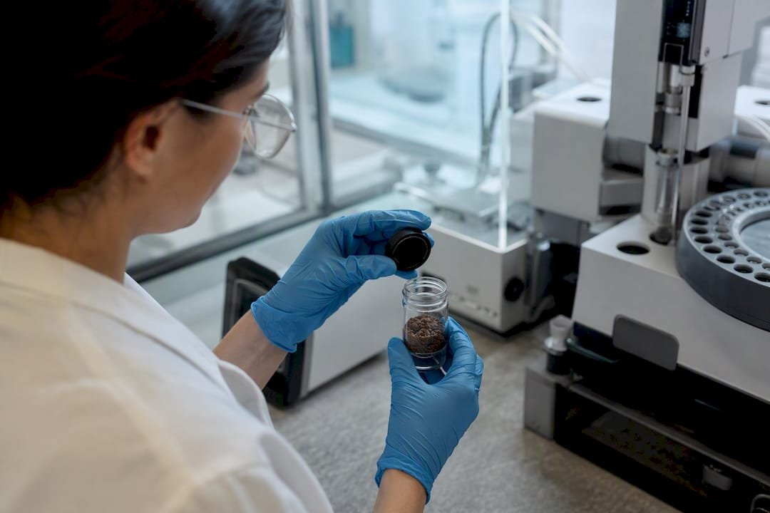 Lab technician handling contaminated soil sample